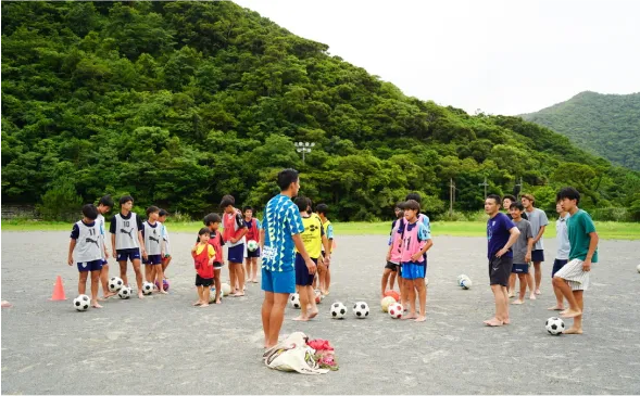 裸足でボールを追う子どもと指導する様子